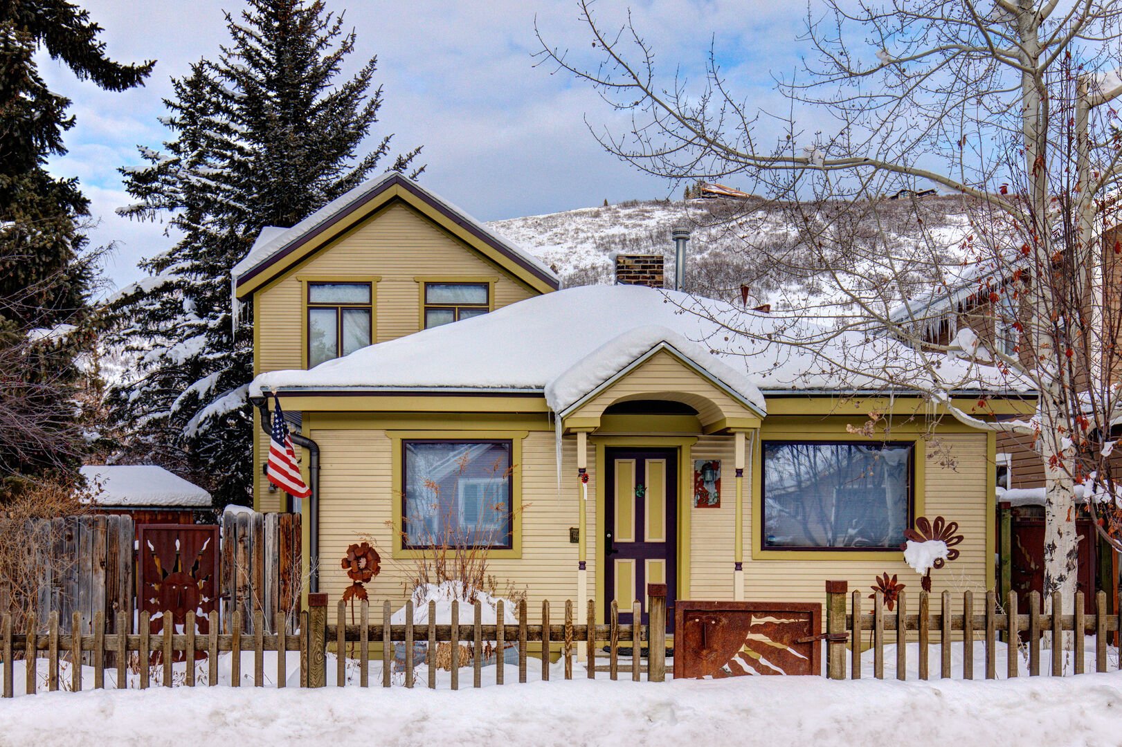 Yellow house with snow on roof